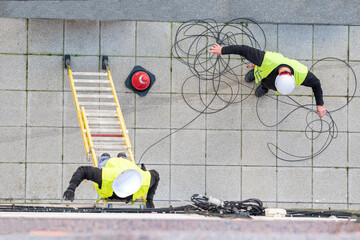 trabajadores de telecomunicaciones instalando fibra óptica y utilizando una escalera