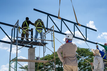 A construction engineer inspects the installation of a factory roof steel frame that uses a mobile crane to lift it up to a height.