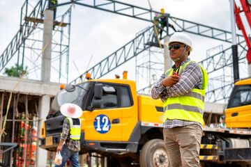 A construction engineer inspects the installation of a factory roof steel frame that uses a mobile crane to lift it up to a height.
