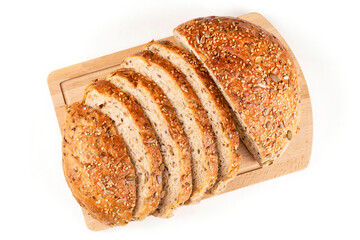 Round whole-grain bread made of wheat flour with the addition of seeds, cut into pieces, lies on a wooden board on a white insulated background. Sourdough bread, without yeast. View from above.