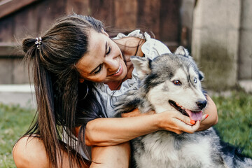  Woman and Dog.Smiling  Beautiful Woman having fun and  hugging  cute siberian Husky Dog at the back Yard .   Woman Playing with her dog durign the summer vacation 