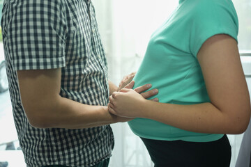 Asian husband stroking pregnant wife's belly