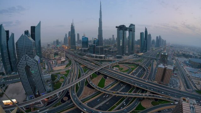Day to night Time lapse of  car traffic in conjunction interchange high rise futuristic concept building in Dubai  from top view with wide angle.