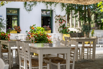 Fototapeta na wymiar Greek outdoors tavern with table and chair at Kithira island Milopotamos village. Pots with flowers.