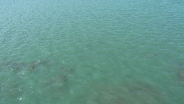 Blue water background, texture. Blue sea water flows gently on the sunny day of summer morning. Sea waves at Rameshwaram beach in Tamilnadu, India.