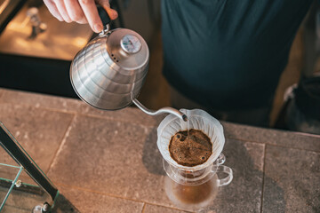 Close up of barista pouring water on coffee ground with filter. Hand drip coffee