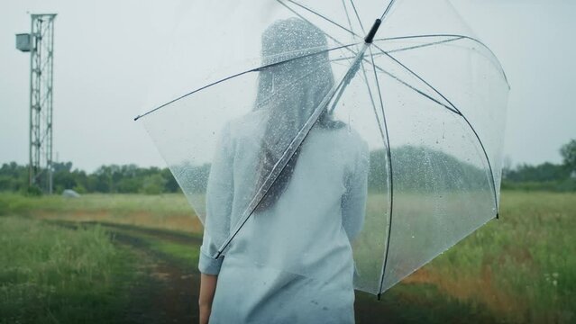 a sad Armenian woman walks in the rain with an umbrella. she enjoys this weather.