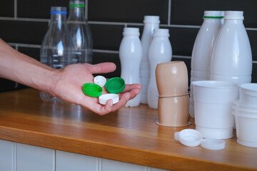person holds of many colored plastic bottle caps in his hand, collect and sort waste for recycling, ecological lifestyle concept