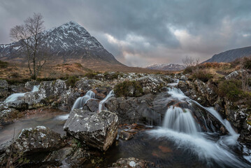 Fototapeta na wymiar Epic majestic Winter sunset landscape of Stob Dearg Buachaille Etive Mor iconic peak in Scottish Highlands with famous River Etive waterfalls in foreground