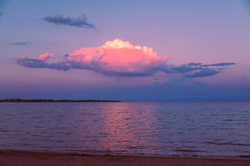 Amazing colorful sunset over lake with huge cloud