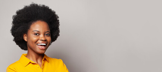 Happy young black woman smiling against white wall background
