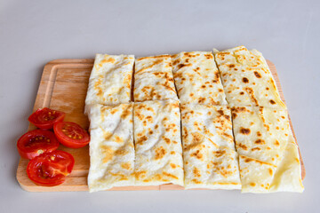 Freshly baked appetizing Turkish tortillas -Gozleme with spinach, cheese  on a wooden board. Shallow depth of  field. Handmade Turkish traditional pastries. Otlu peynirli ispanakli gozleme.