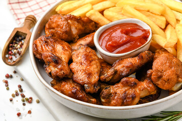 Spicy chicken wings with potatoes fries and ketchup. 