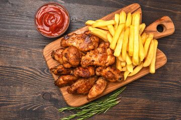 Spicy chicken wings with potatoes fries and ketchup. 