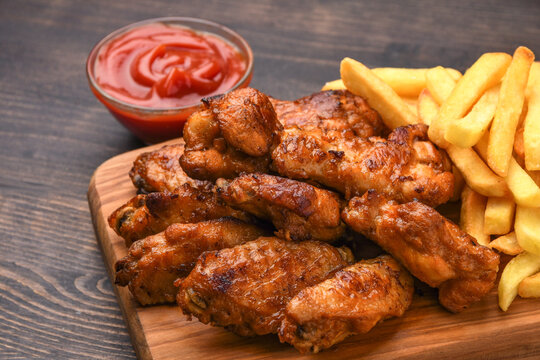Spicy chicken wings with potatoes fries and ketchup. 