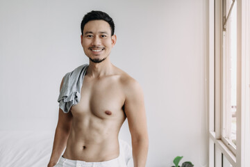 Asian man not wearing top relax after bath in the living room in his apartment.