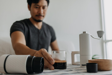 Asian man make and drink his own french press coffee.