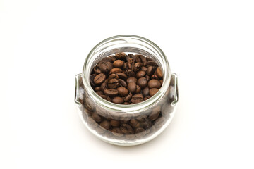 Coffee beans in a glass container on a white background. Close-up