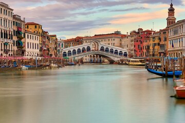 Beautiful shot of the Rialto Bridge over a river and surrounded by colorful buildings, Venice, Italy - obrazy, fototapety, plakaty