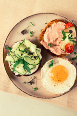 Assortment of sandwiches, white bread, fried egg, cream cheese and cucumber, capelin caviar, sesame bun, breakfast, on a white table, no people,