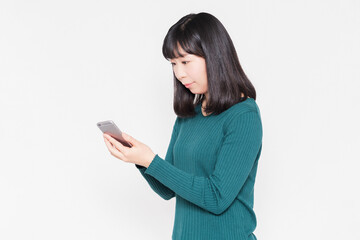 白背景の前でスマホを操作している女性