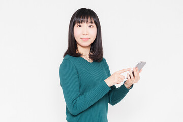 白背景の前でスマホを操作している女性