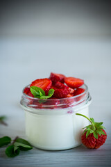 Sweet homemade yogurt with fresh ripe strawberries in a glass jar