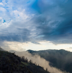 green mountain chain under blue dramatic cloudy sky
