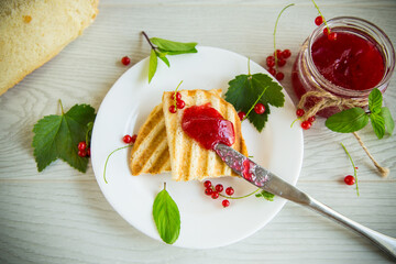 fried bread croutons for breakfast with redcurrant jam in a plate with berries