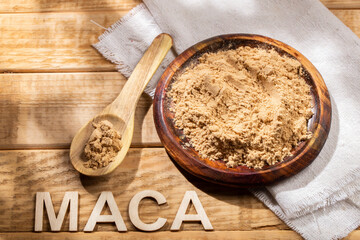 Maca powder, in wooden bowl on the table, nutritional substance from Peru