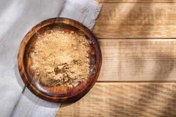 Maca powder, in wooden bowl on the table, nutritional substance from Peru