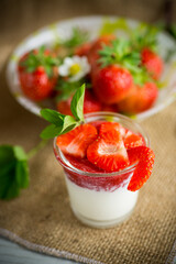 sweet homemade yogurt with strawberry jam and fresh strawberries in a glass cup
