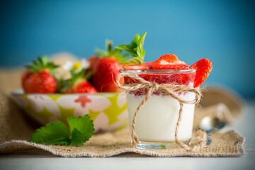 sweet homemade yogurt with strawberry jam and fresh strawberries in a glass cup