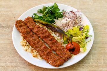 Grilled Turkish Adana, Urfa  Kebab with grilled vegetables, onion and rice on plate. Adana durum.