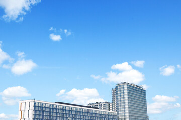 Obraz na płótnie Canvas high-rise glass buildings against blue clouds, empty space for text