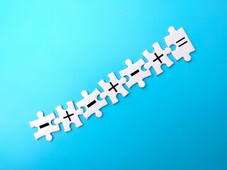 Puzzles with symbols of subtract, add and equal to on blue background-education concept