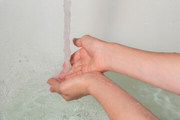 a clean stream of water with splashes falls on a person's hands