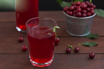 cherry juice in a glass with cherries on a wooden background