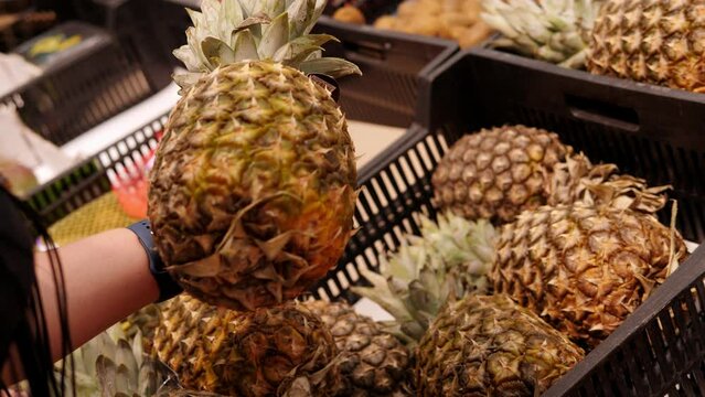 Close-up of a woman holding a pineapple in a supermarket.