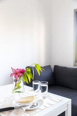 Two glasses of water and a bouquet of eucalyptus and red flowers in a transparent vase on the table.