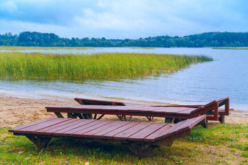 Wooden beds for rest on the shore of a forest lake.