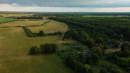 Fototapeta premium Rural landscape at dawn. Green forests and fields in the rays of the rising sun. Aerial photography.