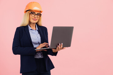 Architect or engineer woman in glasses use laptop on the pink background