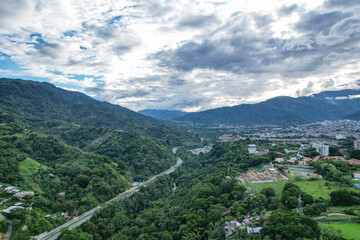 Fototapeta na wymiar Colombia - Ibague, vista de dron con montaña, carretera en ella y vista hacia la ciudad.