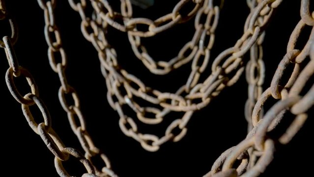 Old metal chain with rusted links on black isolated studio background. Rusty hanging aged chain in dust and dirt. Structure of the metal covered with corrosion. Rough metal chain connections close up.