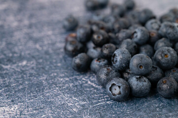 Close-up of a pile of freshly picked blueberries on a dark blue metallic background.