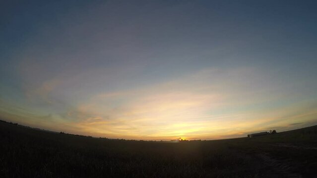 Fisheye view of a colorful sunset over the agricultural landscape of Holland, where a sprinkler system is watering the dry land.