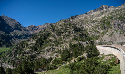 Fototapeta na wymiar road and buildings below a mountain dam and reservoir