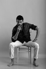 Young man sitting on a chair in black and white