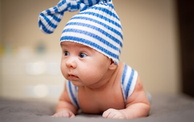 Funny portrait boy in hat. Small cute baby lying on the bed.